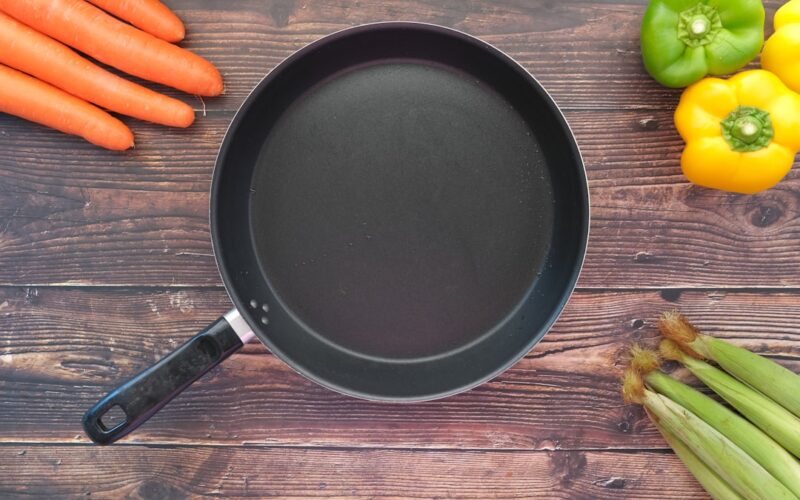 empty frying pan and vegetables on table .