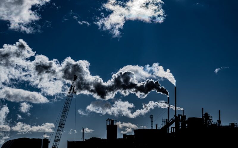 silhouette of a factory and the smoke it's emitting